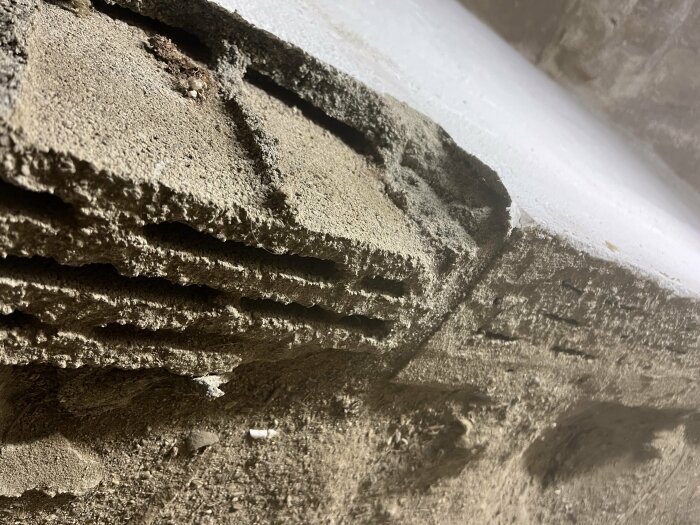 En närbild av betonghålsten och en kompakt betongvägg i en jordkällare, troligen byggd 1927, som kan innehålla blåbetong.