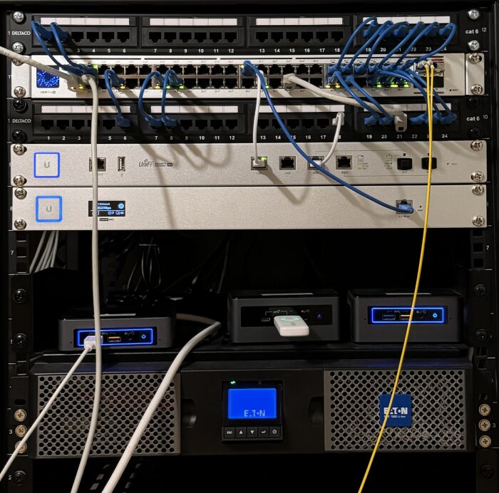 Ett rackmonterat nätverkssystem med patchpaneler, nätverksomkopplare, servrar, kablar och en uninterruptible power supply (UPS)-enhet i en serverrumsmiljö.