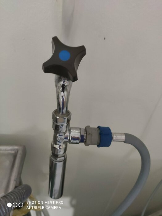 Bilden visar en tryckstötdämpare installerad på en vattenledning, rör och ventil med en blå markering på handtaget.