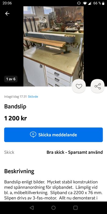 Bandslipmaskin på ett arbetsbord i en verkstad. Verkstaden har flera verktyg och verktygslådor i bakgrunden.