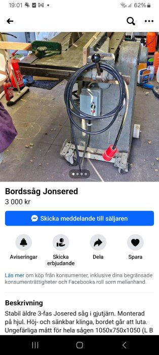 Bordssåg av märket Jonsered med elkabel och rörlig bas på hjul, placerad i en verkstad med brandsläckare och annan utrustning i bakgrunden.