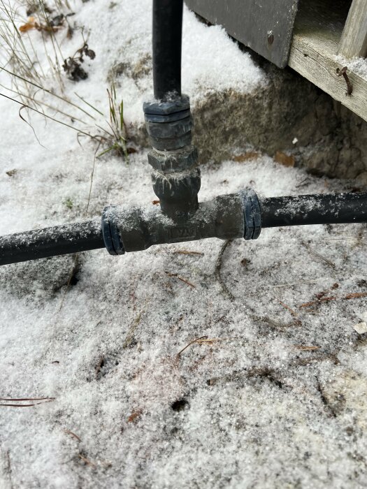 Vattenledningar med kopplingar under en snötäckt markyta, anslutna till en stuga.