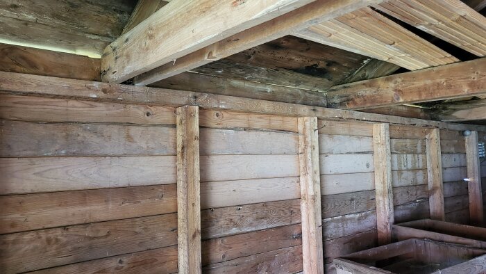 Insidan av ett gammalt garagetak med träreglar och takstolar i behov av förstärkning.