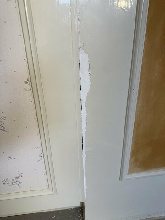 Spricka mellan garderob och vägg med gipsvägg och målad yta, sönderfall av fogmassa synligt.