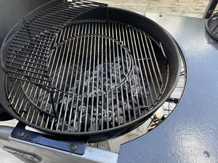 En kolgrill med briketter redo för att grilla fläskfilé, korv, tomater och rödbetor.