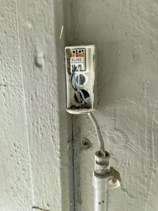 En närbild av en elektronisk givare på en vägg med flera kablar anslutna som verkar leda till ett pannrum i en källare.