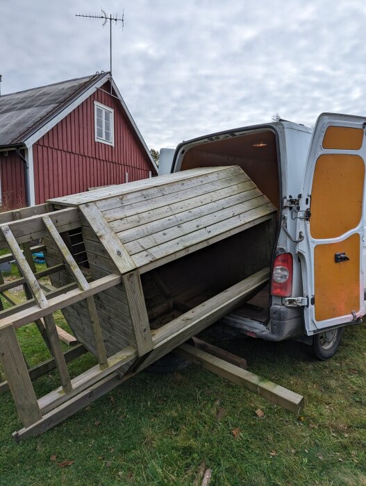 Den nedmonterade lekställningen lastas in i en öppen skåpbil med en lada och ett rött hus i bakgrunden.