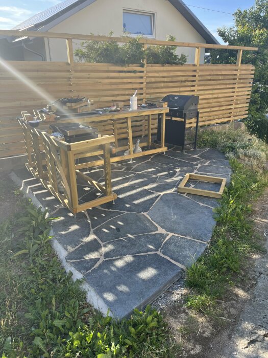 Stommar byggda på stenlagd yta med bord och grill; justeringsbara fötter används för att ställa in höjd och jämna ut ojämnheter i stenläggningen.