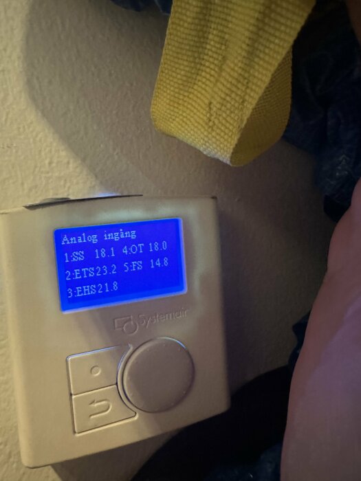 Bilden visar en digital display med texten "Analog ingång" från en enhet märkt Systemair. Skärmen visar värden för olika givare (SSS, ETS, EHS).