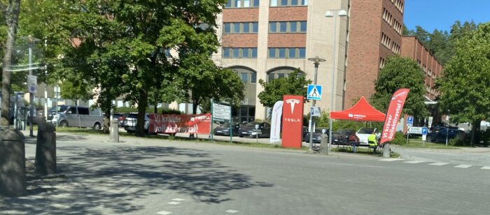 Partytält, banderoller och flaggor uppsatta på parkeringsplats framför en kontorsbyggnad, med text om fackliga krav och kollektivavtal.