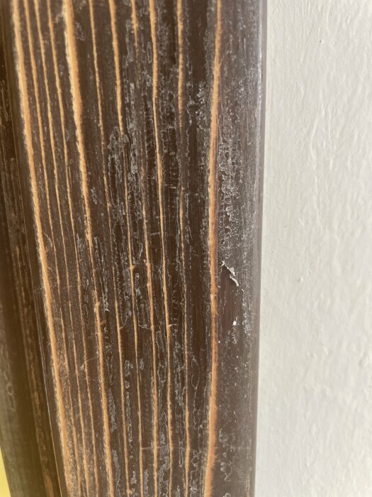 Närbild på en slipad dörrkarm med synliga lim- eller lackrester som kan skrapas bort.