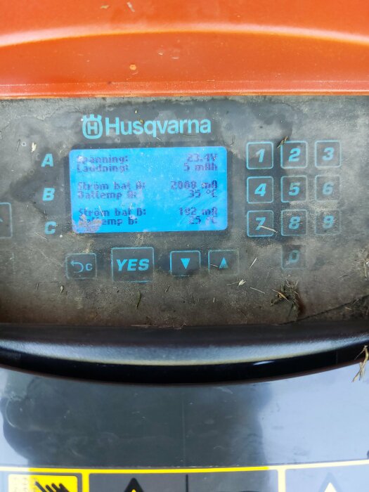 Displayen på en Husqvarna Automower som visar status för batteriladdning med följande texter: Spänning 23.4V, laddning 9 min, ström bå 3000mA, temp 33°C.