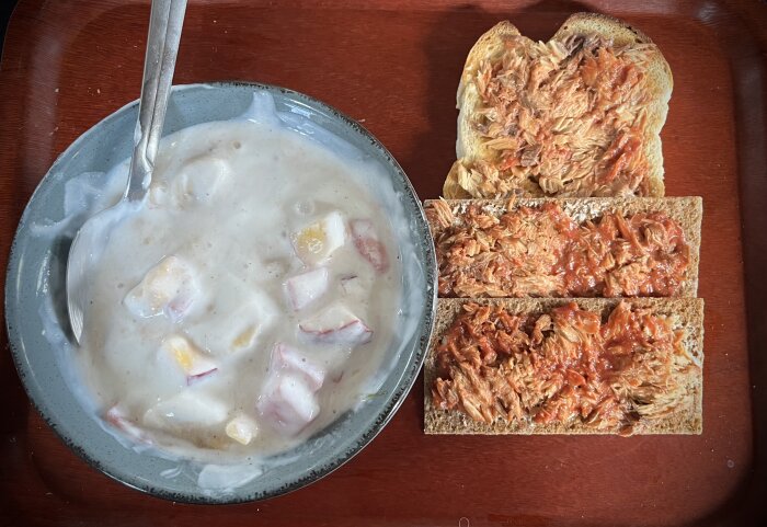 En skål med kvarg eller fil och fruktsallad bredvid knäckebröd med makrill i tomatsås.