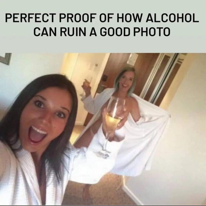 Två kvinnor i vita badrockar, en med ett vinglas, tar en selfie. Kvinnan i bakgrunden råkar visa mer än avsett. Texten ovanför bilden: "PERFECT PROOF OF HOW ALCOHOL CAN RUIN A GOOD PHOTO".