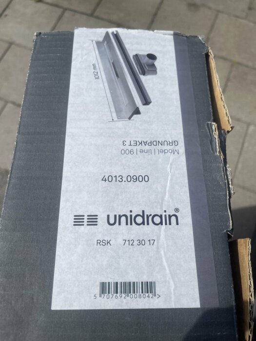 Unidrain linjebrunnsproduktpaket i kartong, märkt med modell 900 Grundpaket 3, inkluderas avloppsram och specifikationer.