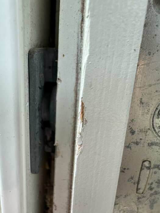 Koppelhakar saknas på en slitna ram av en altandörr, vilket gör det svårt att dela på fönsterrutorna.