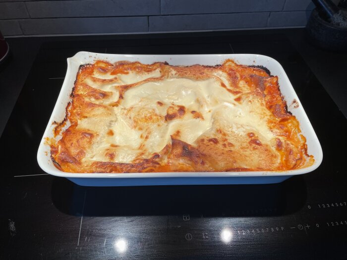 Hemlagad lasagne i en vit ugnsform, nygräddad med gyllene oststekt topp.