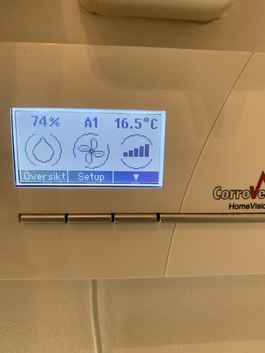 Bild av mätdonets display på avfuktare som visar fuktighet på 74 %, en A1-symbol och temperatur på 16,5 °C. Texten "Översikt" och "Setup" visas.