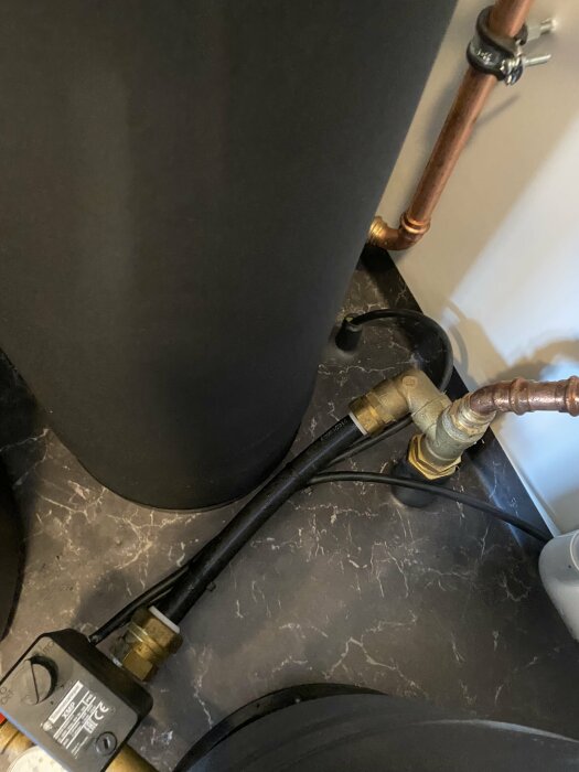 Hydrofor och filteranläggning i tvättstuga med kopparrör, svart isolering på rör och vattenledning som visar kondensbildning och liten glipa i isoleringen.