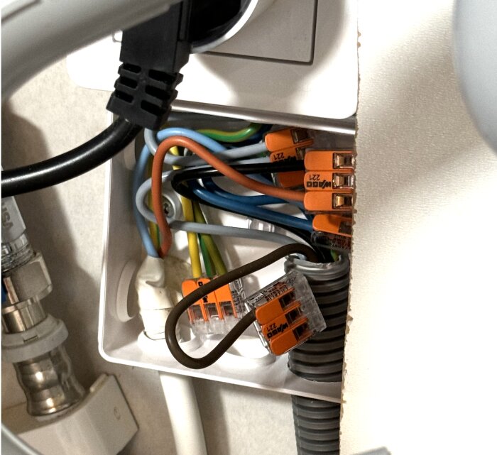 Elektrisk dosa med flera anslutna kablar, där en brun kabel är felkopplad istället för en svart kabel.