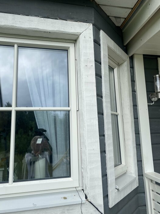 Bild på grått hus med vitt fönster där träpanelen runt fönstret verkar ha öppnats för inspektion.