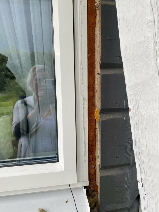 Närbild av ett fönster med en synlig remsa av brun isolering och gullfiber runt ramen, vilket diskuteras i inlägget om kall luft som drar in på vintern.