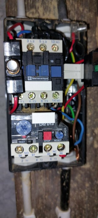 Kontaktormotorstyrning från Telemechanique med flera kablar anslutna. Visar terminalerna och knappar för test, stop och reset.