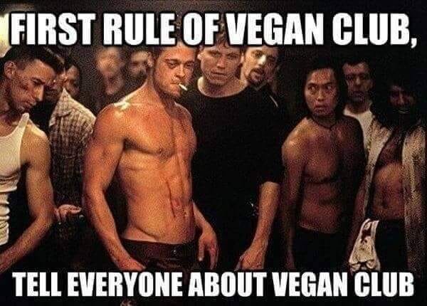 Män utan tröja står allvarligt i ett mörkt rum, med texten "FIRST RULE OF VEGAN CLUB, TELL EVERYONE ABOUT VEGAN CLUB" överskridande bilden.