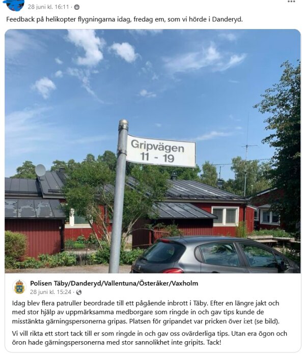 Skylt med texten "Gripvägen 11-19" framför ett rött hus med svarta tak och parkerad bil under blå himmel med moln.