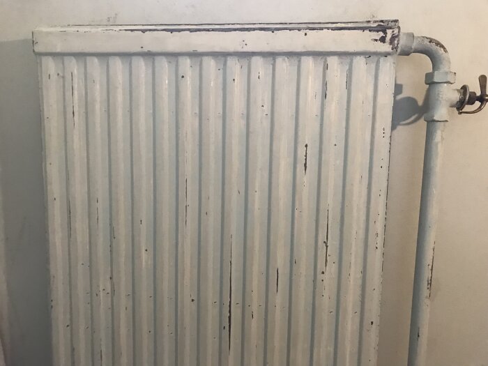 Gammal radiator med avskavd turkos färg efter att ha skrapats och slipats.