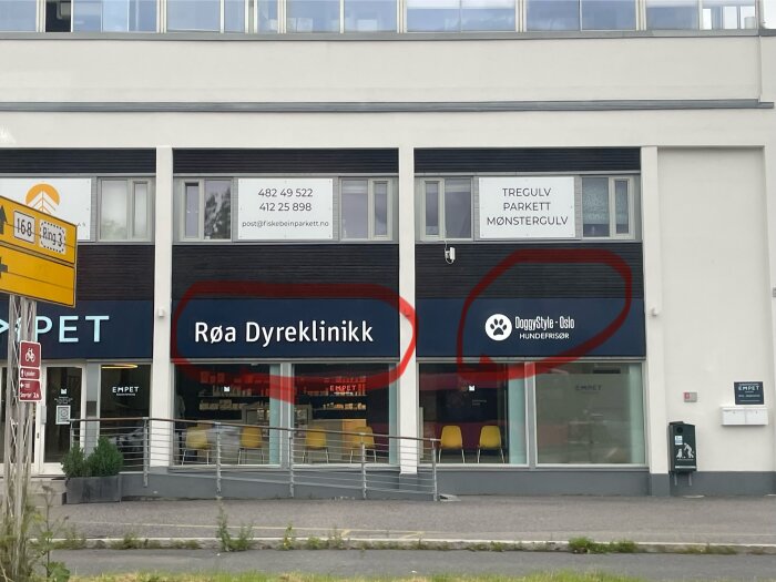 Skyltar för "Røa Dyreklinikk" och "DoggyStyle - Oslo Hundefrisør" på en byggnad i västra Norge.