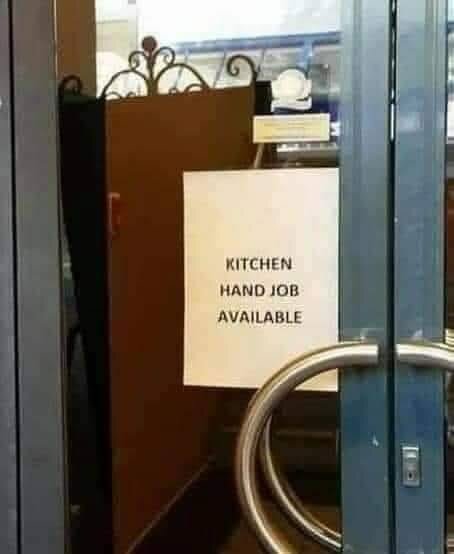 En skylt på en glasdörr med texten "KITCHEN HAND JOB AVAILABLE" som verkar innehålla en stavningsmiss.