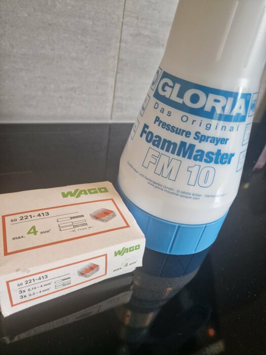 Gloria FoamMaster tryckspruta FM 10 och en låda Wago 221-413 kopplingsklämmor på en svart yta.