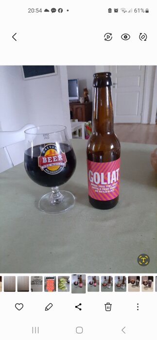 Flaska Goliat imperial stout från To Øl bredvid ett glas med mörk öl på ett bord. Glaset har texten "BEER AND WHISKY FESTIVAL MALMÖMÄSSAN".