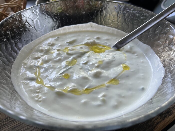 Skål med tzatziki smaksatt med smulad fetaost och toppad med olivolja.
