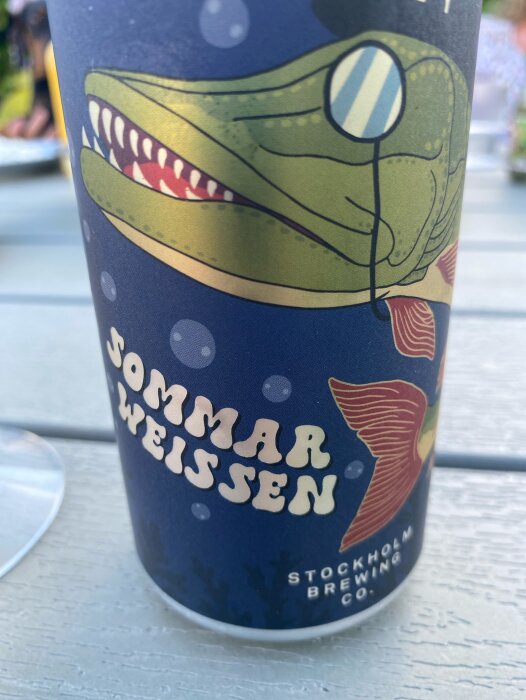 Närbild på en ölburk med texten "Sommarweissen" och en tecknad krokodil som bär monokel. Brus från Stockholm Brewing Co.