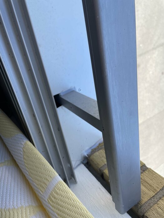 Glipa mellan räcket och fönstren på en inglasad balkong, med isoleringsmaterial synligt.