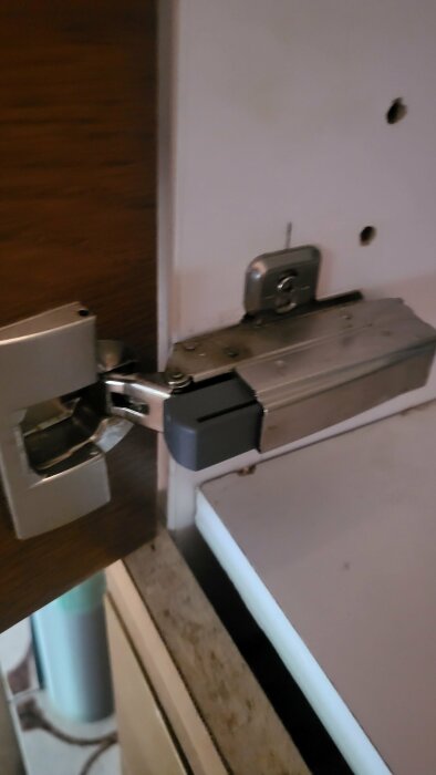 Skåpsgångjärn med softclose-mekanism installerat på insidan av ett köksskåp.