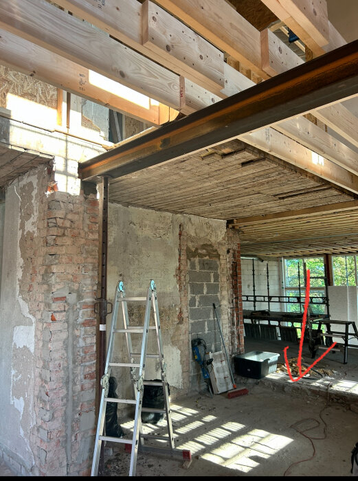 Bild på byggarbetsplats med förberett golv, en aluminiumsstege, murade väggar, verktyg och ett rött handritat märke som visar en nivåskillnad i golvet.