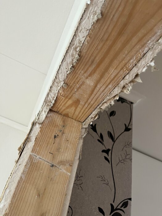 Nyupptagen dörröppning i vägg med synligt träregel och trasigt gips.