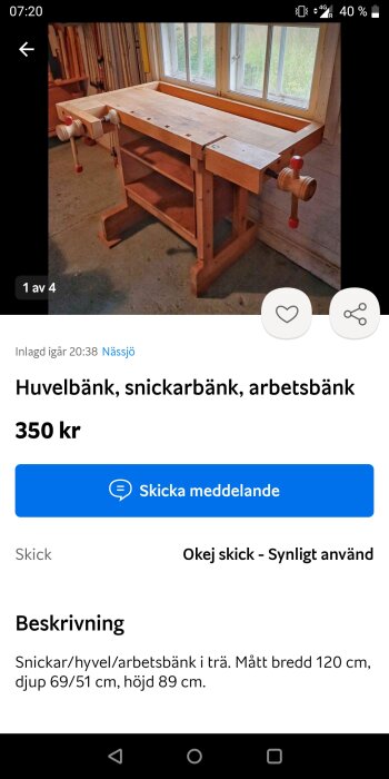 Trä snickarbänk med skruvstycken och hyllor, placerad vid ett fönster i en verkstad. Bänken kostar 350 kr och är i okej skick.