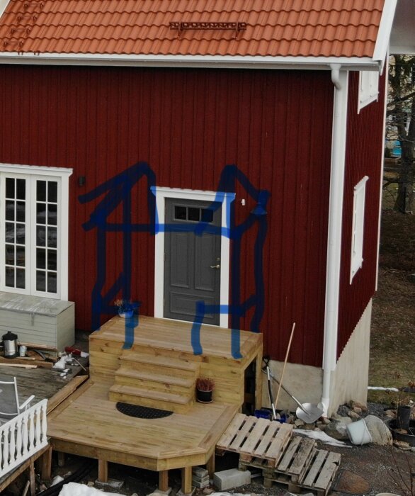 Principskiss i blått på en röd fasad, med föreslaget tak och stolpar för altanens takkonstruktion, ovanpå en nybyggd trall och trappa.