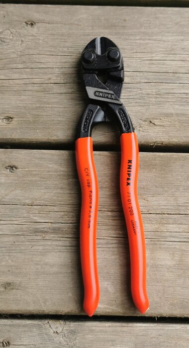 Knipex CoBolt bultsax med orange handtag, placerad på en träyta.