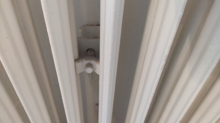 Närbild av fäste och sektioner på en vit radiator som används för att diskutera en eventuell flytt av radiatorn till vänster med 6cm.