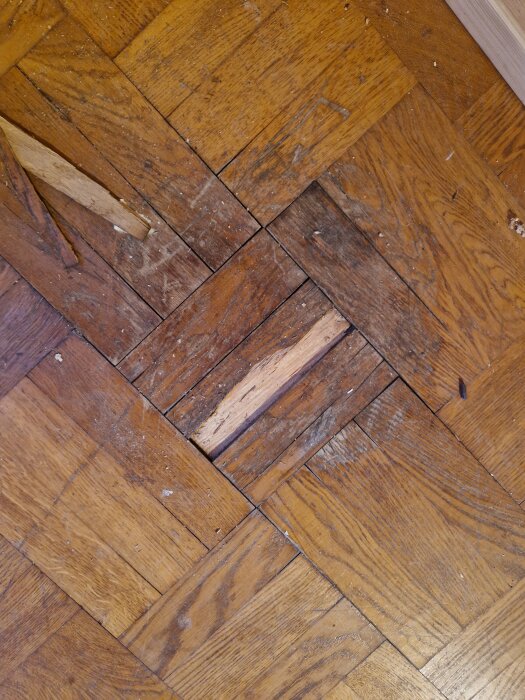 Fuktskadad parkett från 50-talet där stavar saknas och golvspill syns.
