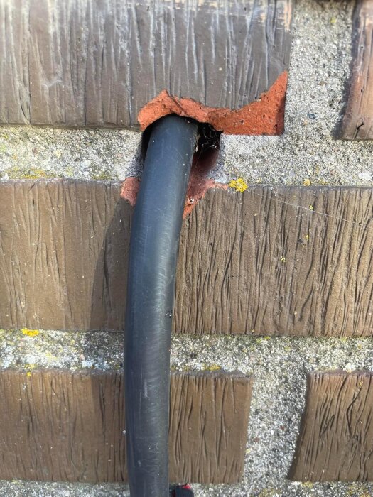 Svart kabel dragen genom hål i tegelvägg vid nyinstallation av laddbox.