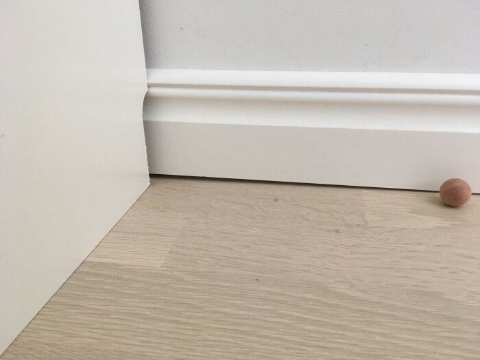 En list som installerats ojämnt vid golvet, där en tydlig glipa syns mellan listen och golvet vid ena väggen.