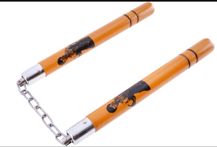 Ett nunchaku av trä med orange färg och en kedja som förbinder de två pinnarna.