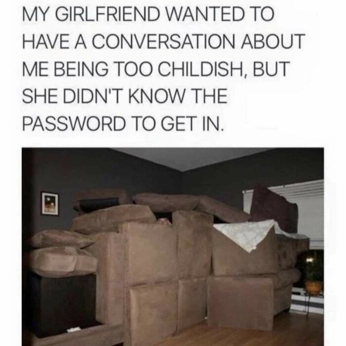 En fort byggd av soffkuddar i ett vardagsrum med text ovanför som säger att pojkvännen ansågs barnslig, men flickvännen inte kände till lösenordet för att komma in.