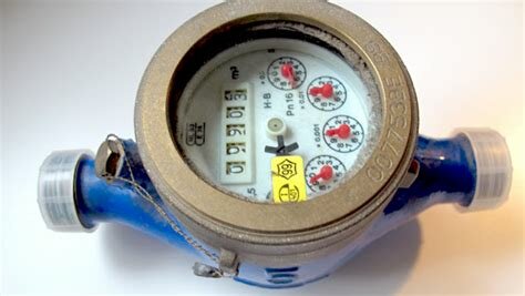 Bild på en blå vattenmätare med fyra roterande visare och en digital avläsning som visar förbrukningen i kubikmeter (m³).
